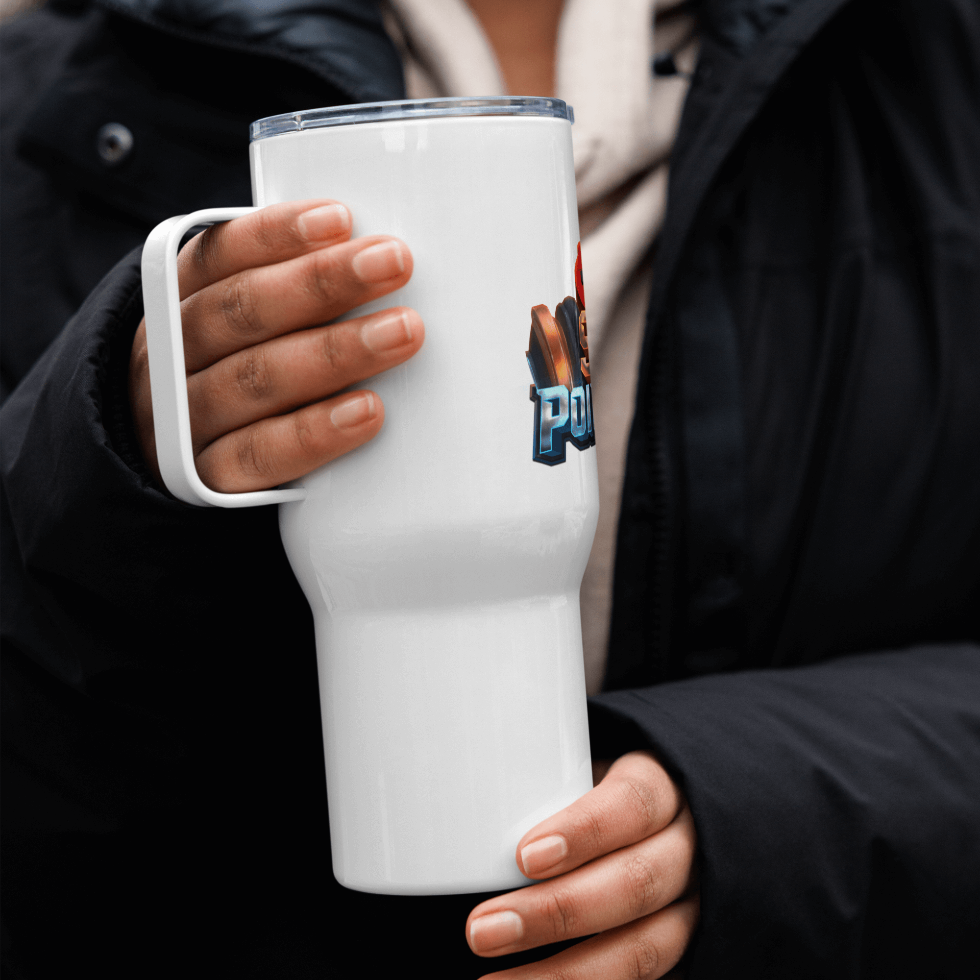 Person holding a white travel mug with handle, featuring a colorful design, perfect for commuting and adventures.